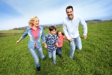 Family of four running together in natural landscape
